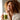 Woman in a white robe drinking a green smoothie with a straw.