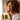 Woman in a white robe drinking a green smoothie with a straw.