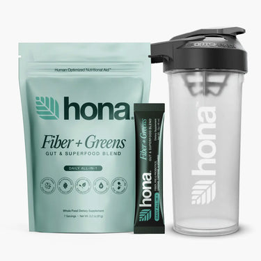 Hona Fiber + Greens package, single serving stick pack, and clear shaker bottle on a white background