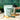 Hona Fiber + Greens package, shaker bottle, and stick pack on a wooden cutting board with a green tiled wall background.